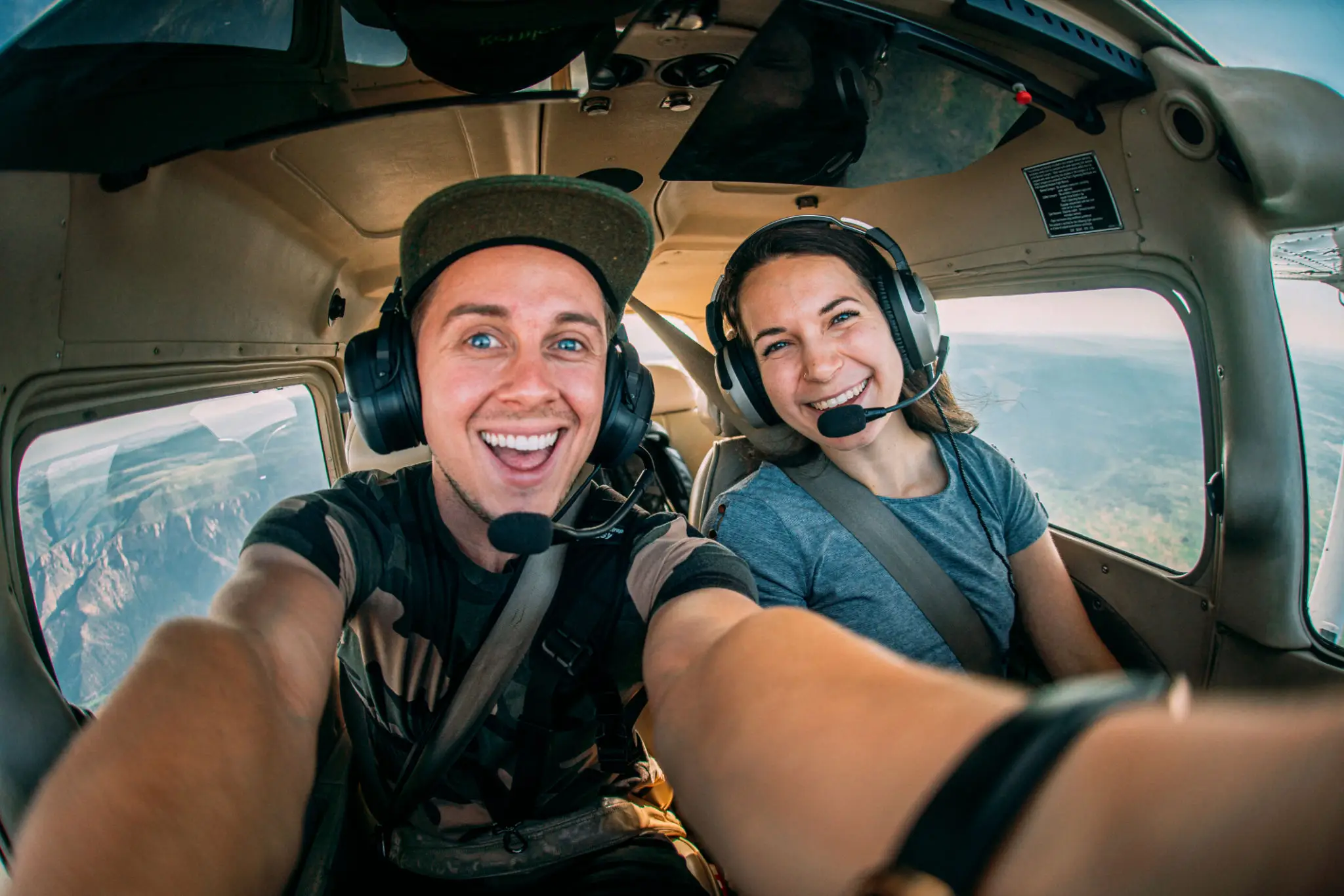 Two friends taking a selfie inside a small aircraft cockpit.