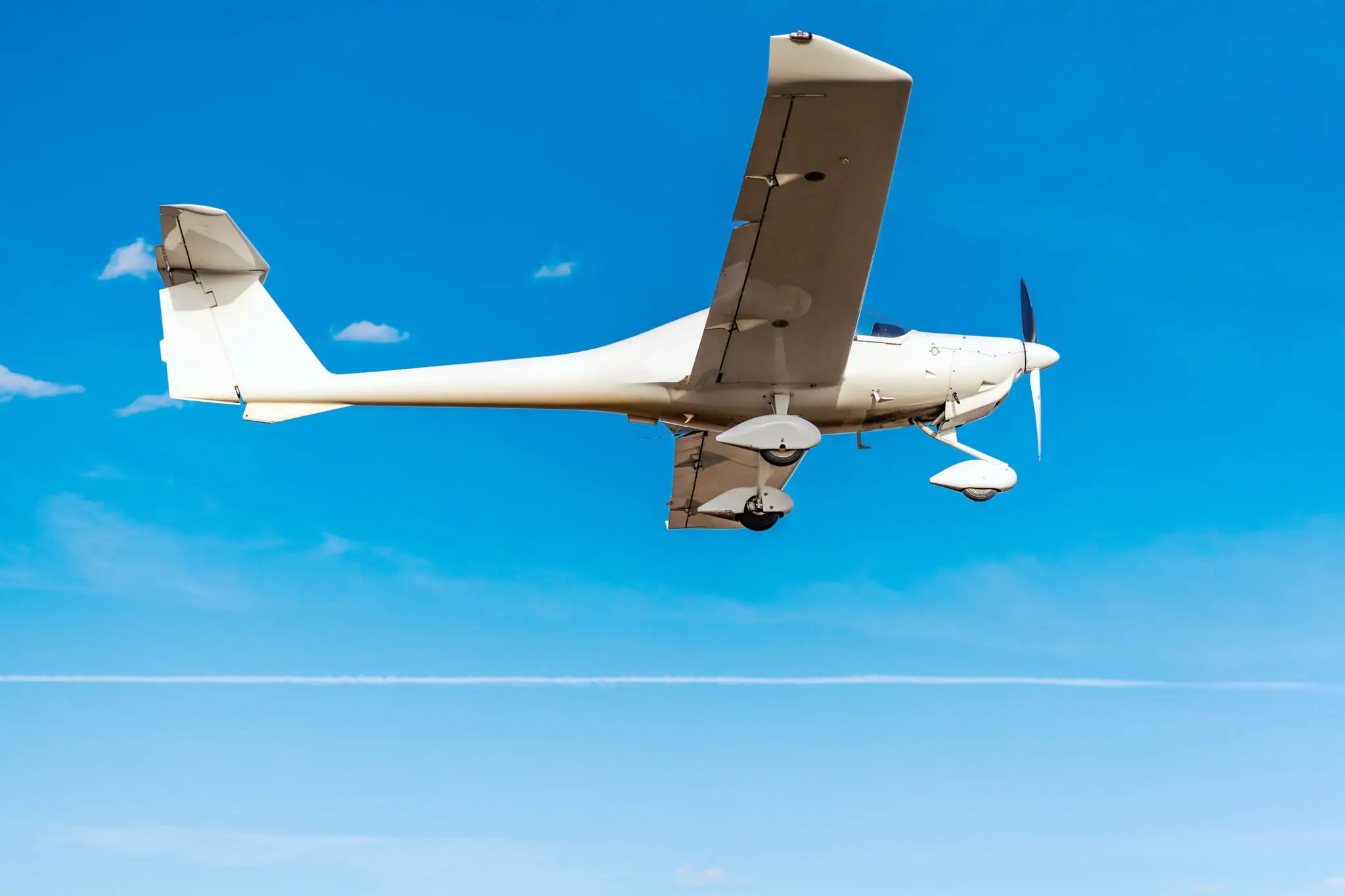 A small white airplane flying in a clear blue sky.